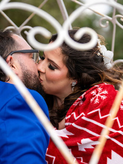 Bride and groom kissing during wedding portrait session with decorative arch