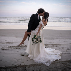 Bride and groom kissing on the beach during romantic wedding portrait session