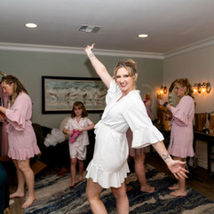 Bride dancing joyfully with bridesmaids during getting ready moments
