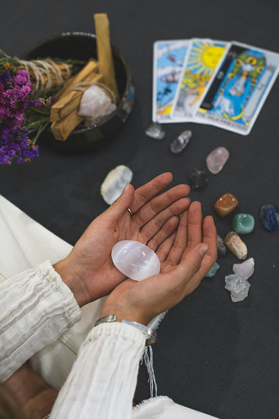 Hands holding a crystal with tarot cards on the table below