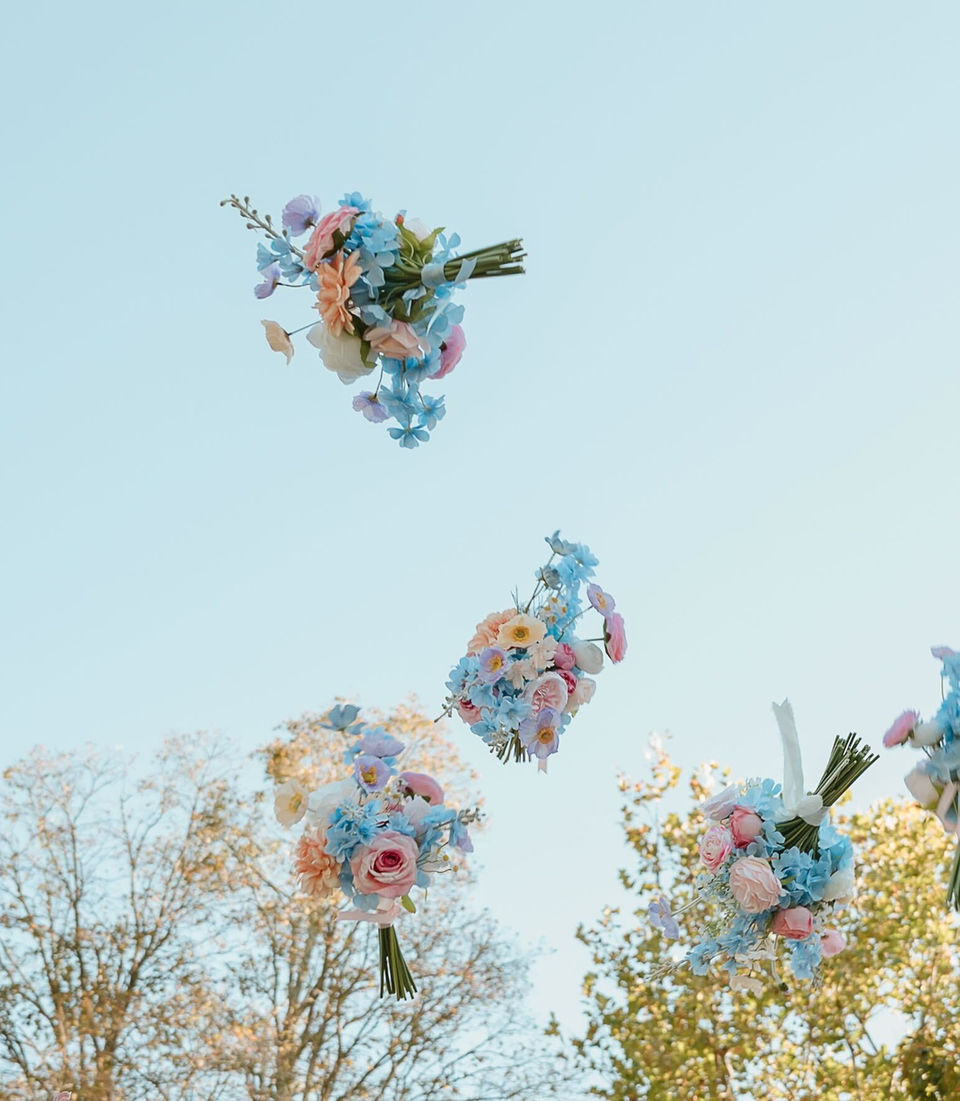 Bride and bridesmaids tossing their bridal bouquets up in the air on the wedding day.