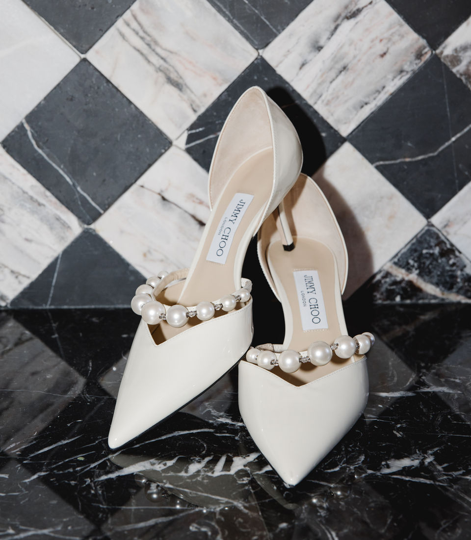 A pair of chic designer Jimmy Choo wedding shoes positioned against a black and white checkered background.