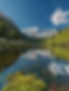 A clear lake reflecting mountains and trees in colors, symbolizing harmony and healing through somatic therapy.