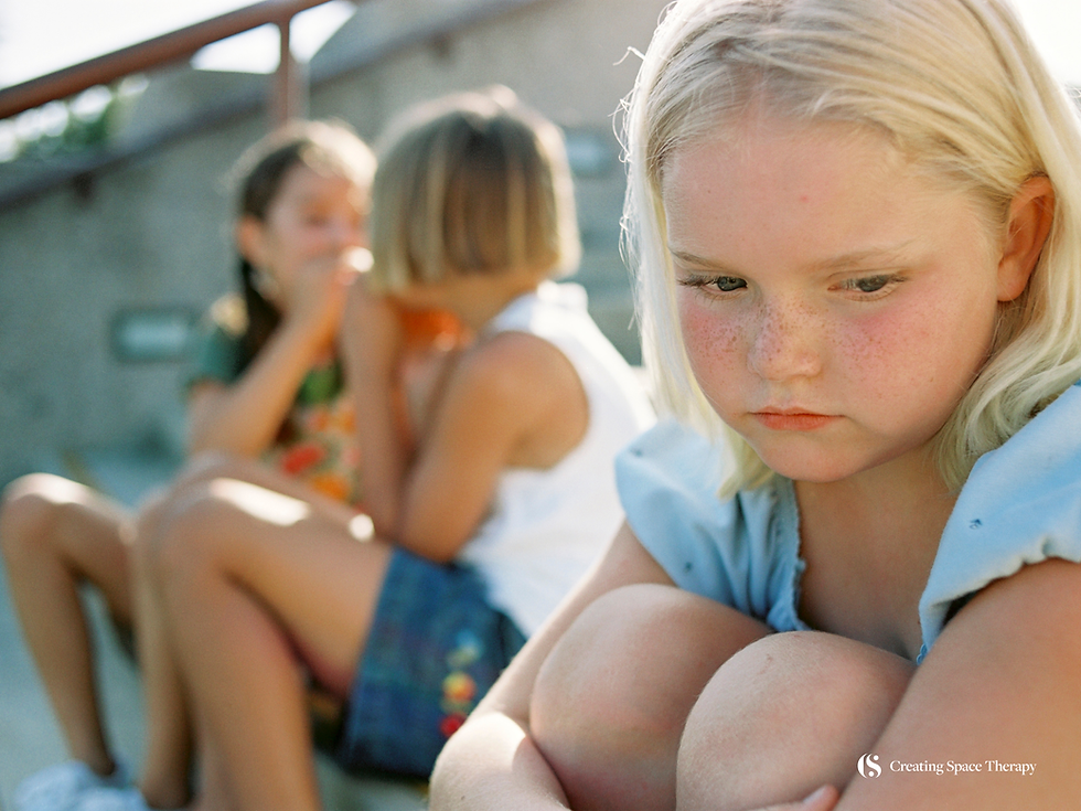 Young girl sitting apart from classmates, looking sad and withdrawn, illustrating subtle behavior changes adults may notice in children.