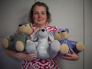 Deborah Jameson, a trusted handmade memory bear maker, holding a collection of finished memory bears made from loved ones' clothing