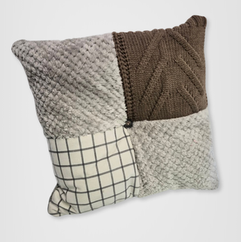Square patchwork memory cushion handcrafted from a dad's brown cable-knit cardigan, grey textured fleece sweaters, and a cream and black checked blanket.