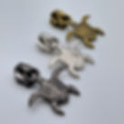Turtle zipper pulls in gunmetal, silver, and brass finishes, displayed in a staggered row on a light background.