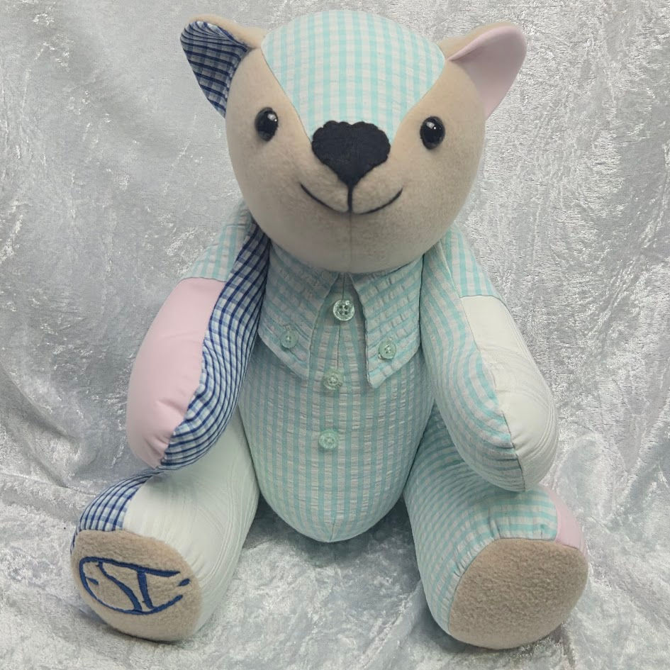 A handmade memory bear for Durham families, crafted from blue and pink patterned clothing with a shirt‑style design and personalised embroidery on the foot.