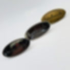 Three oval metal bag labels with the word 'handmade' engraved, shown in gunmetal, silver, and antique brass finishes on a whi