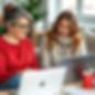 Middle aged woman sitting and looking at a computer with a hispanic woman.jpg