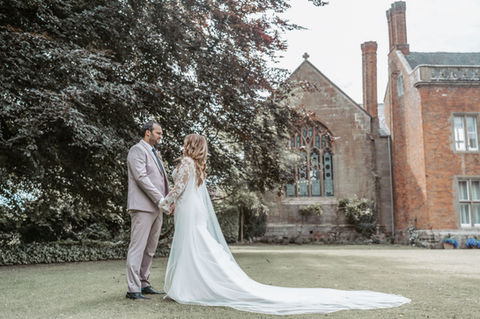 Bride and groom holding hands, standing in front of a church, Mo Photography