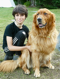 A boys poses with the camp dog