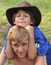 Two campers pose while one of them wears a large hat
