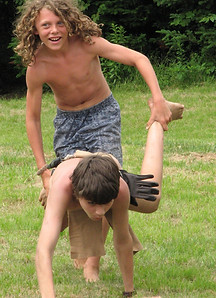 Two campers run a wheelbarrow race during field day