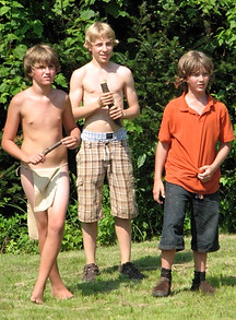 Three boys playing Sticks in camp