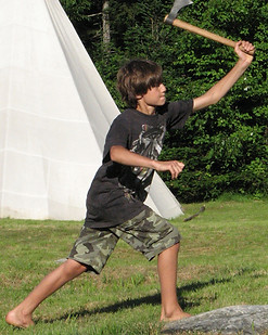 A barefoot boy throwing a tomahawk