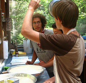 Counselor and boys making pizza