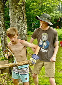 A counselor showing a camper how to use a saw properly