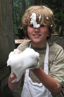 A boy in an apron plays with soap bubbles