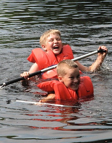 Two boys paddling a swamped canoe