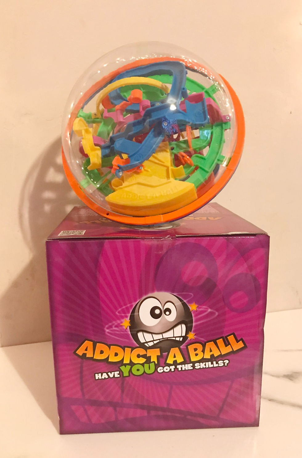 the colourfull ball shaped puzzle sat on top of it box with a pink background waiting to be played with by beautifullyoriginal.com