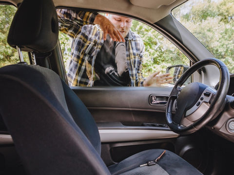 Man trying to retrieve his keys from his car after they got locked in