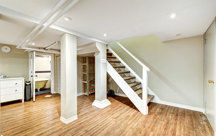 Renovated basement with hardwood floors, white columns, and a staircase - a stunning basement renovation transformation.