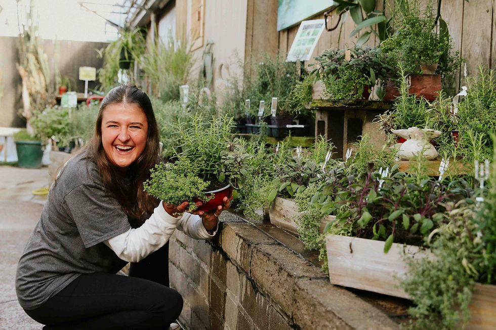 Smiling person next to an herb garden