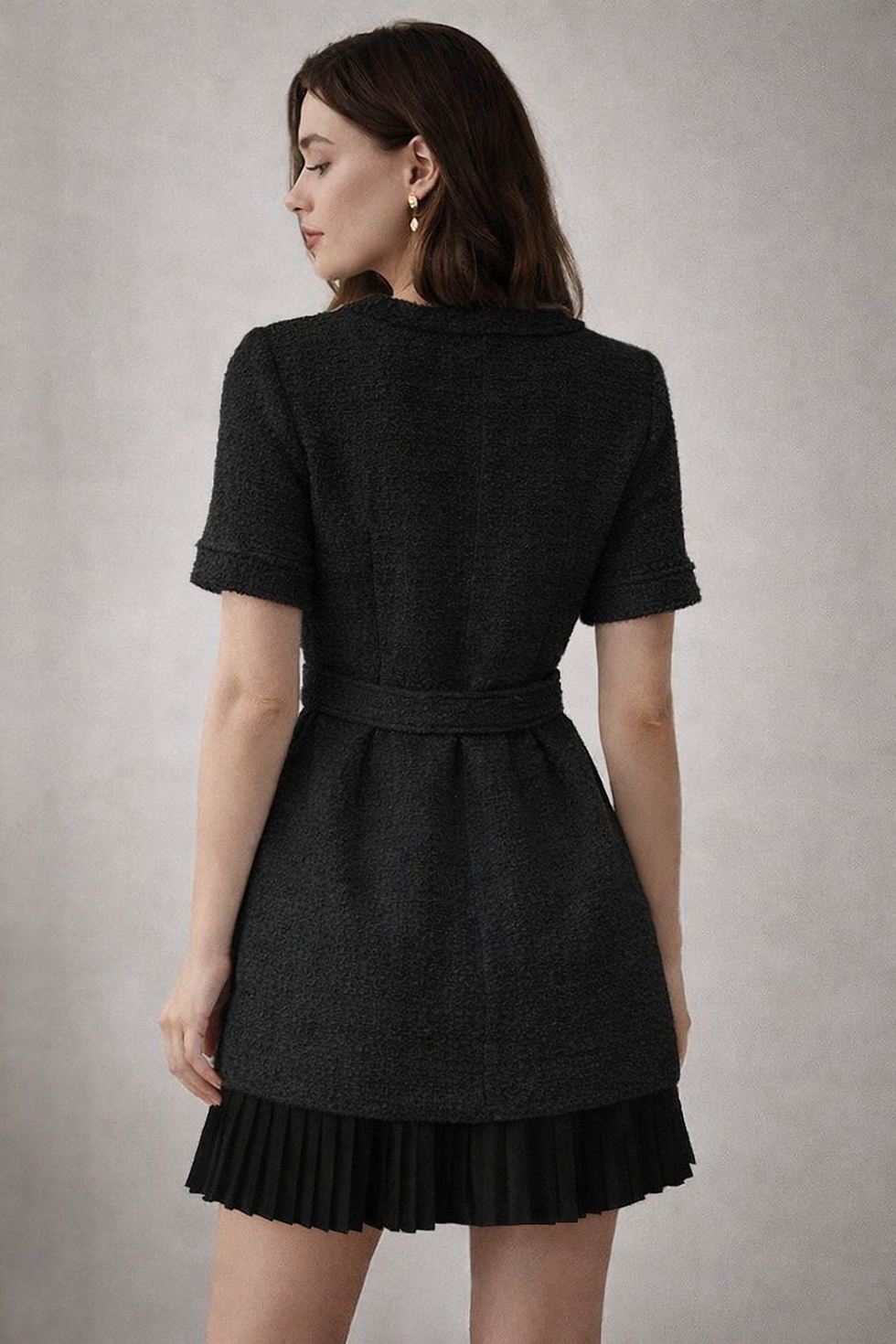 Miniature : Woman in dark belted dress with pleated skirt, back view.