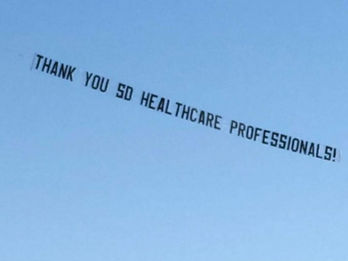 Sky banner featuring the message "THANK YOU SD HEALTHCARE PROFESSIONALS!" in black block letters, flying against a clear blue sky, created in collaboration with The Skywriters to honor San Diego's frontline workers, showcasing precision aerial advertising and high-impact event marketing, creative wide area messaging services, and thoughtful airplane sky banners.