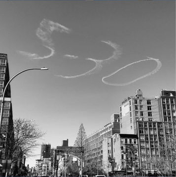 5-30 skywriting message in flowing cloud letters above a black and white urban cityscape in New York City, created in collaboration with The Skywriters, showcasing precision skytyping, skywriting, aerial advertising, creative airplane messages, and viral marketing opportunities.