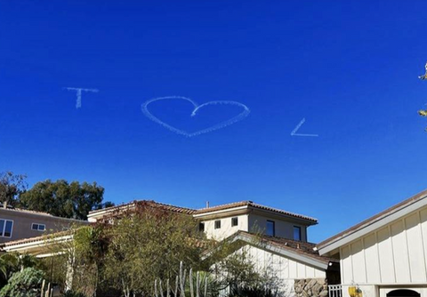 Marriage proposal event for a couple, while an airplane skywriting I Heart You message flies in the distance against a bright blue sky, created in collaboration with The Skywriters, showcasing professional aerial banner advertising, unique marriage proposal ideas, and high-impact aerial messaging for romantic celebrations.
