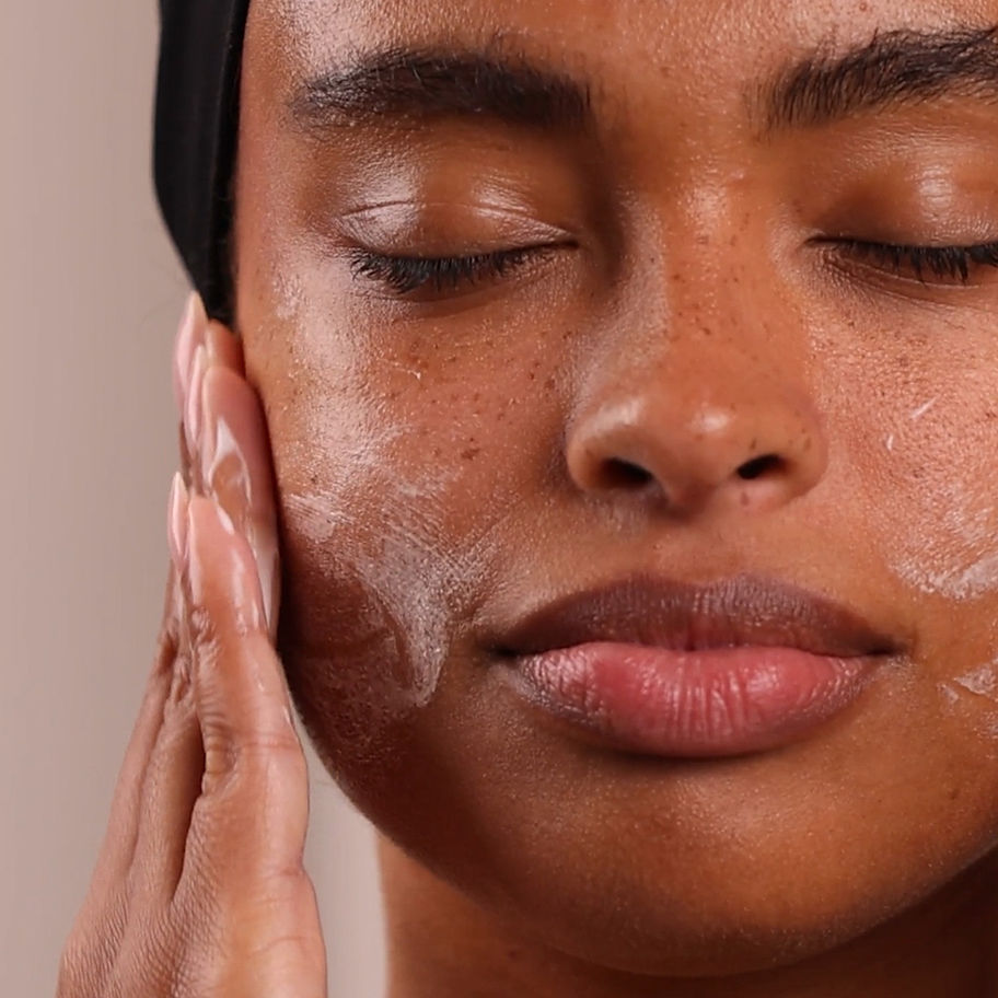 Woman applying facial cleanser, eyes closed, Radiant Protection SPF Fluid, skincare routine, Update - Skin by Tae