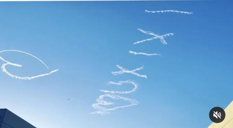 QUXIXI skywriting message in flowing cursive letters with a heart symbol in the clear blue sky, created in collaboration with The Skywriters, showcasing precision skytyping, skywriting, aerial advertising, high-impact event marketing, and personalized airplane messages.