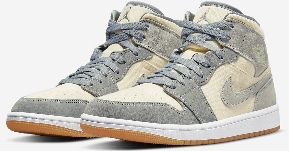 A close-up photo of a pair of Air Jordan 1 Mid sneakers in gray and white.