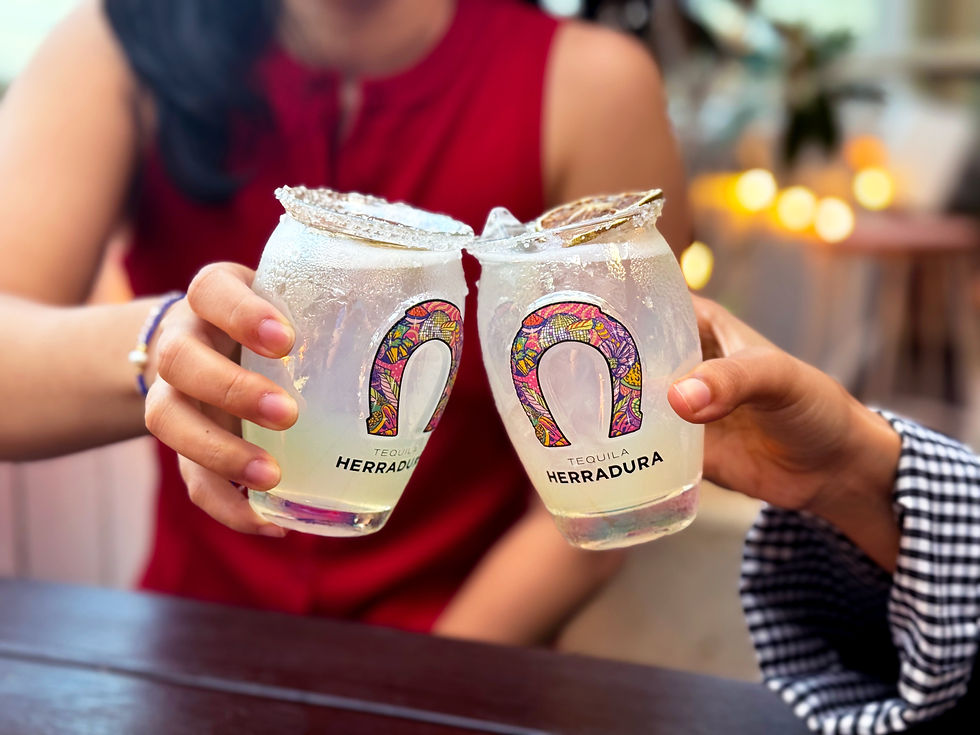 Two friends enjoying margaritas in a Herradura tequila glass at a rooftop bar