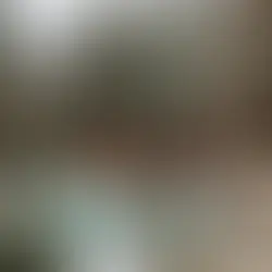 Snowy patio with a hot tub, red lounge chairs, and a wooden cabin surrounded by snowy trees. Peaceful, wintry setting.