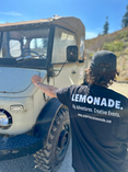 LEMONADE EVENTS AND EXPERIENCES staff worker, wearing a logo t-shirt takes a break against an old-school british truck
