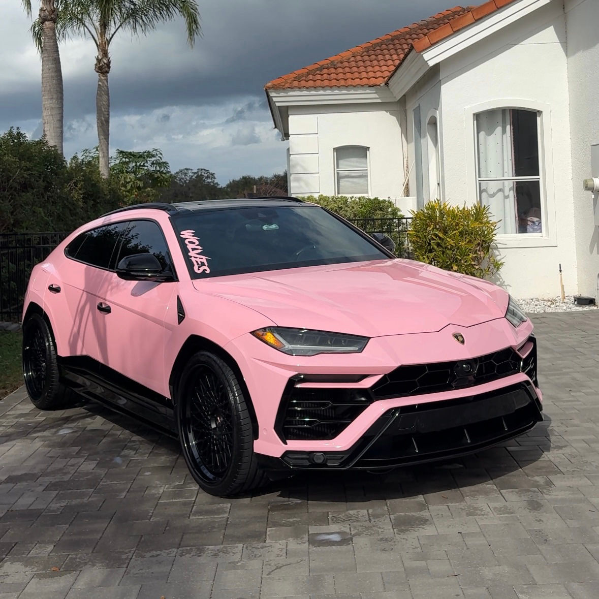 Pink Lamborghini Urus parked outside a house