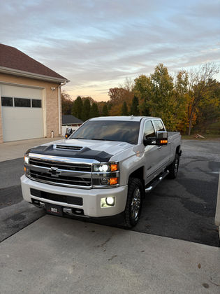 White Chevrolet truck parked on a driveway with partial hood wrap and headlight restoration.