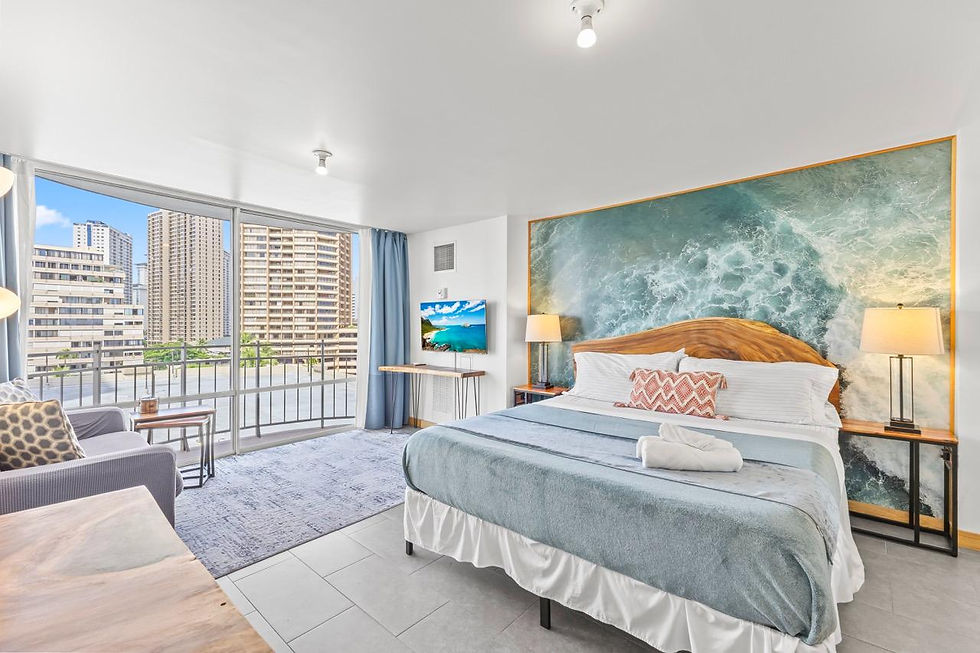 Bright studio with a king bed, ocean-inspired accent wall, and private balcony with city views