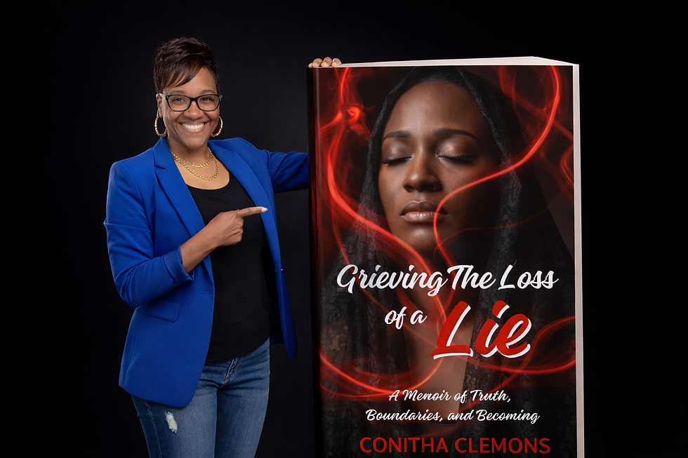 Professional promotional image of author Conitha Clemons standing beside an oversized copy of her memoir Grieving the Loss of a Lie, wearing a blue blazer and smiling while pointing at the book cover, which features a serene woman surrounded by red smoke on a dark background.