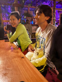 Two retreat guests smiling at the group table with a new cat friend on a guest's lap.