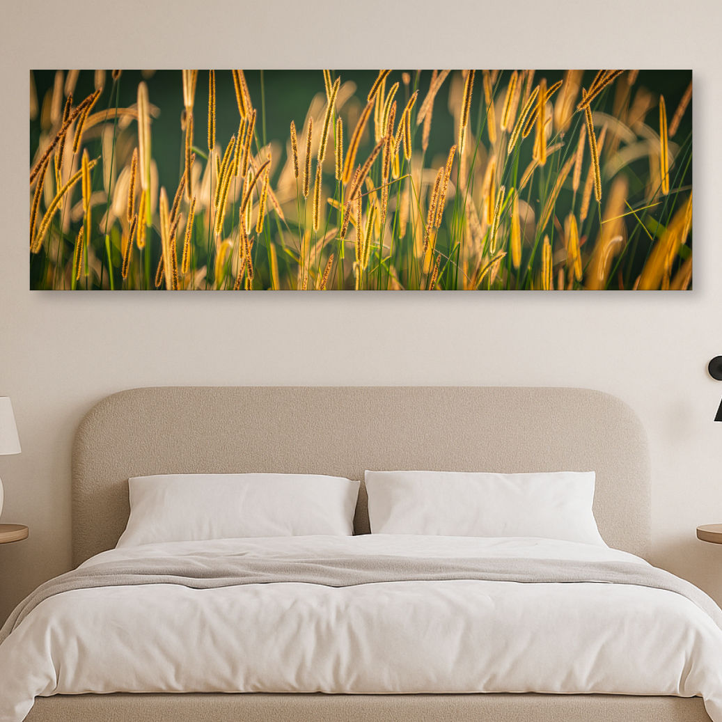 Metallic glass print hanging on the wall above a bed, showing golden sunlit grasses