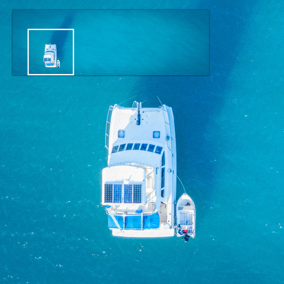 Top-down close-up of a white yacht’s deck and solar panels floating on brilliant turquoise water.