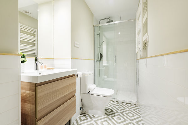 Newly renovated bathroom with small wooden cabinet with drawers and white porcelain sink,