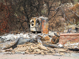 The results of not following dryer vent safety tips can mean a house fire caused by the dryer. This image shows a home that is no longer standing, rubble all around a washer and dryer that were exposed to fire and no longer functional.