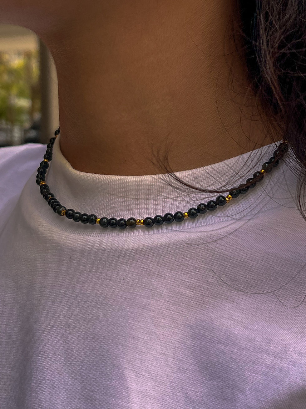 שרשרת חרוזים שחורה על צוואר של אישה, עם חרוזי זהב. Handmade Bliss