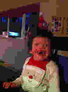 Carys in her Christmas gear beaming at the camera and enjoying her Christmas dinner.