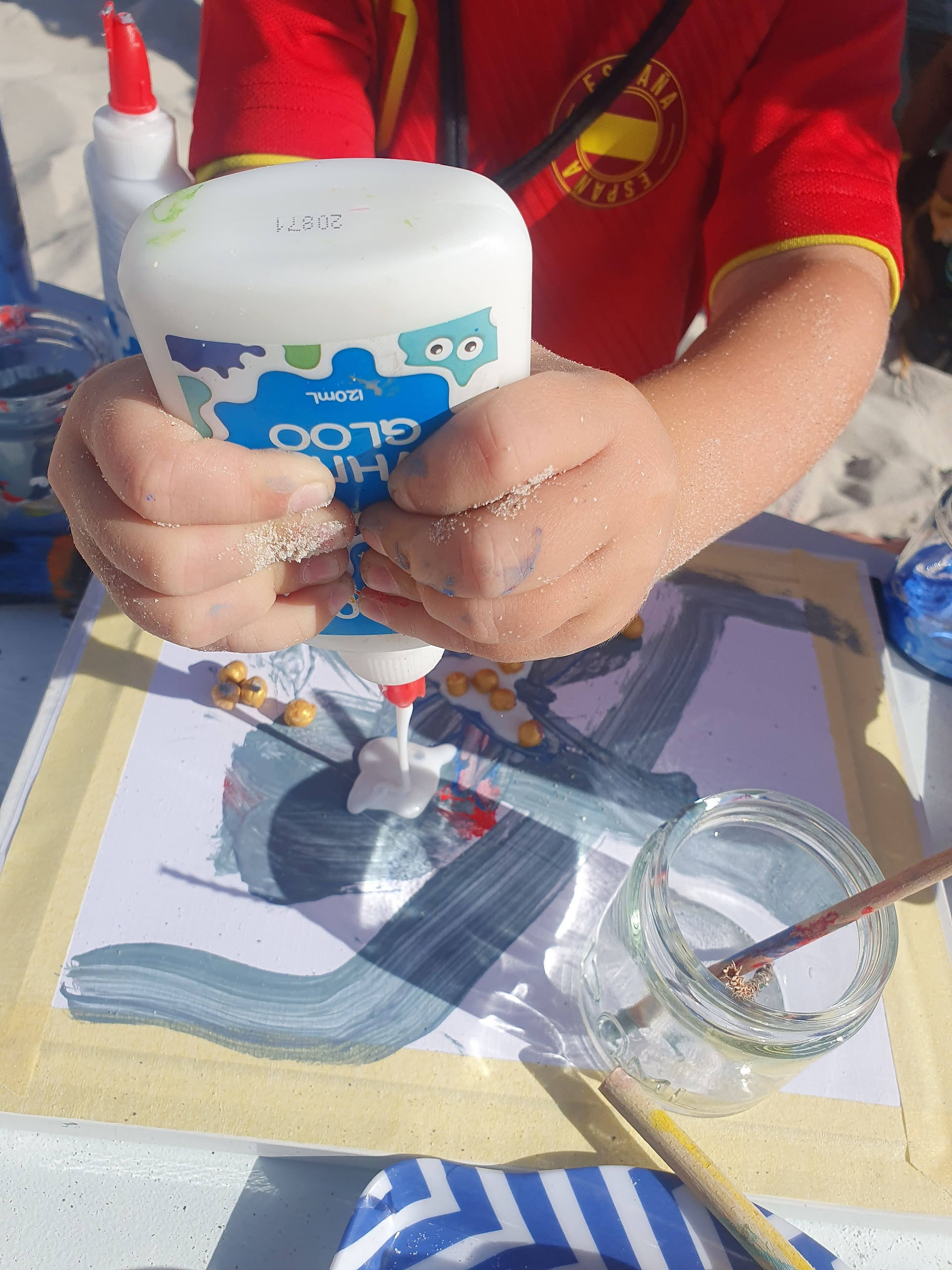 Child is using fine motor skills to add glue to their picture